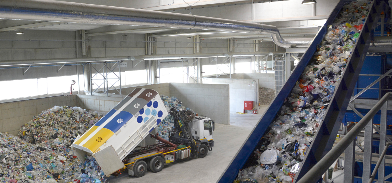Recycling facility in Spresiano with a truck unloading waste beside a conveyor of collected materials