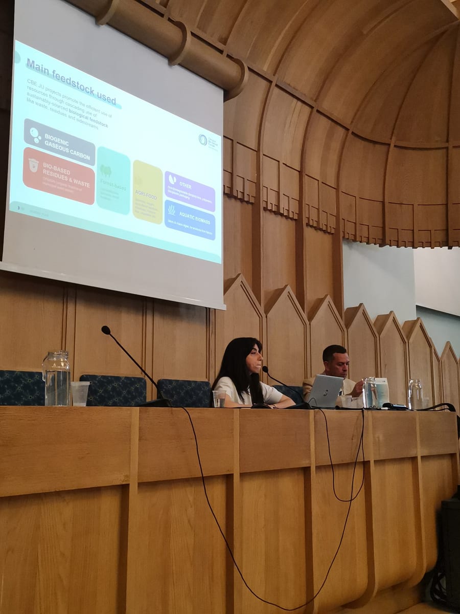A speaker at the table beneath a CBE JU slide on the main feedstocks used by its projects
